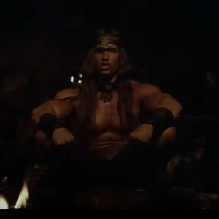 Conan sitting in a dark tavern scene from the 1982 Conan the Barbarian film
